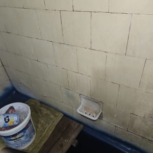 קיר אריחים עם סימני רטיבות, דלי על מגבת