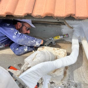 אדם משתמש באקדח סיליקון לאיטום גג