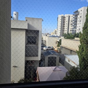 רשת יונים מותקנת על חלון עם נוף לבניינים