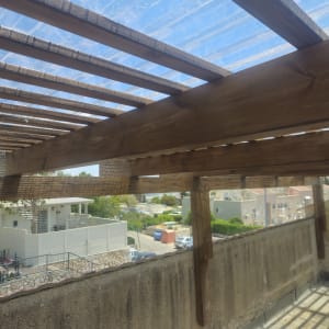 רשת מתוחה על פרגולה מעץ למניעת כניסת יונים