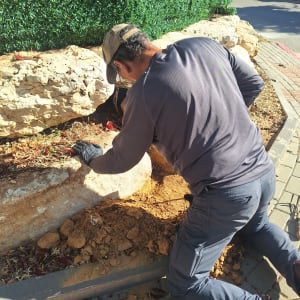 אדם עובד על חפירה ליד קיר ירוק