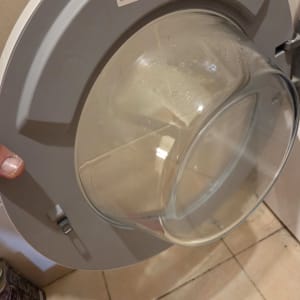 דלת מכונת כביסה פתוחה עם תווית יצרן