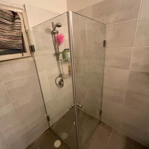 מקלחון זכוכית עם ראש מקלחת ומדף מוצרים