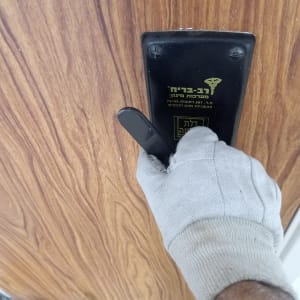 יד עם כפפה מחזיקה ידית דלת על רקע עץ