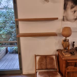 מדף עץ מותקן על קיר ליד כיסא וארונית עץ