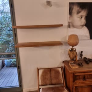 מדף עץ מותקן על קיר ליד כיסא וארונית עץ