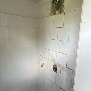חדר אמבטיה עם אריחים לבנים וברזים חשופים