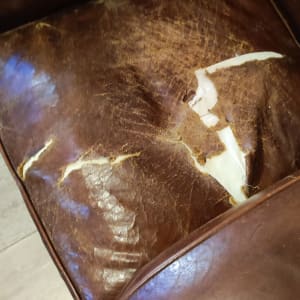 ריפוד עור חום קרוע ובלוי על כורסה