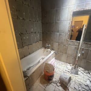 חדר אמבטיה בשיפוץ עם אריחים שבורים ודלי