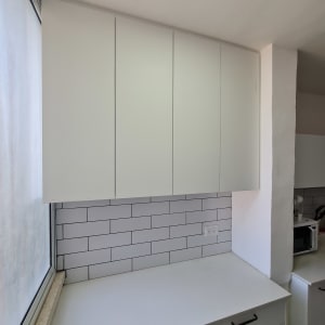 ארונות מטבח לבנים עם משטח עבודה לבן ואריחי קיר לבנים