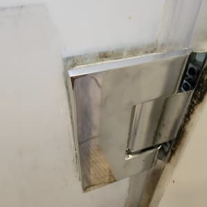 ידית מתכת על דלת מקלחת עם סימני עובש