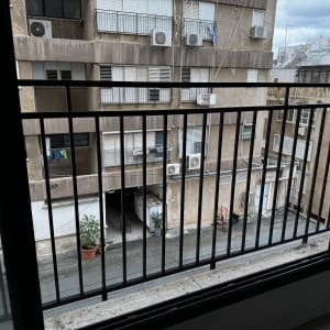 מעקה ברזל שחור במרפסת מול בניין מגורים