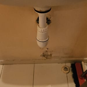 כיור עם צינור ניקוז וקיר פגום