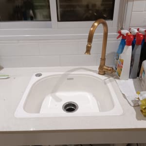 כיור מטבח עם ברז זהב ומוצרי ניקוי