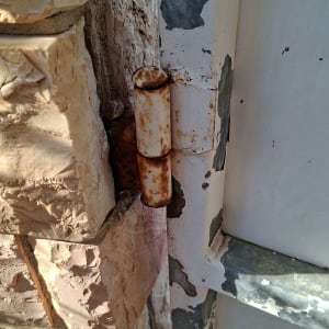 ציר חלוד על קיר אבן ומתכת