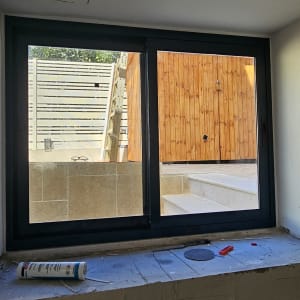 חלון אלומיניום עם מסגרת כהה וחומרי עבודה
