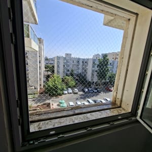 רשת שקופה נגד יונים המותקנת על פתח חלון בבניין מגורים