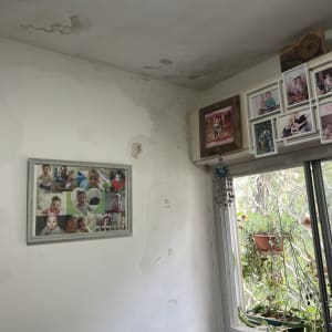 קיר עם סימני רטיבות ותמונות משפחתיות