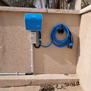 עמדת טעינה כחולה לרכב חשמלי על קיר חיצוני