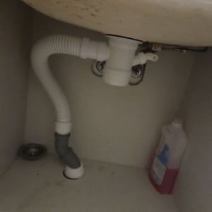 צנרת מתחת לכיור עם בקבוק חומר ניקוי