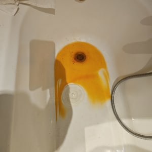 כתם צהוב באמבטיה עם צינור מתכת