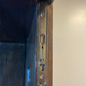 מנגנון נעילה מתכתי בדלת עץ כהה