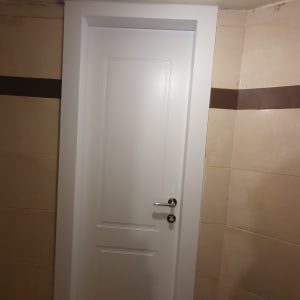 דלת לבנה עם ידית כסופה על קיר אריחים