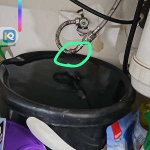 צינור מים גמיש דולף מתחת לכיור לתוך דלי