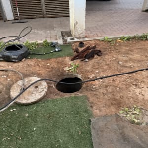 עבודת תחזוקה עם צינור וכלים ליד פתח ביוב