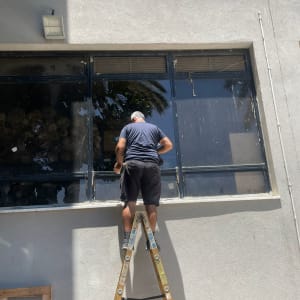 אדם על סולם מתקן חלון זכוכית