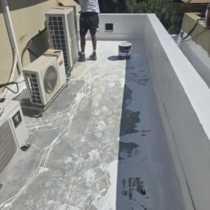 אדם מורח חומר איטום על גג עם מברשת