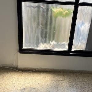 חלון עם מסגרת שחורה וקיר צבוע לבן