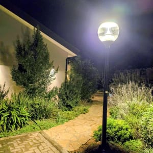 מנורת רחוב מוארת בלילה ליד שביל וגינה