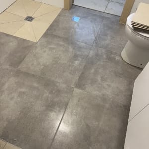 רצפת חדר אמבטיה עם אריחים חדשים ודלת פתוחה