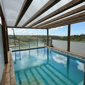 בריכה עם גג עץ ונוף טבעי ברקע