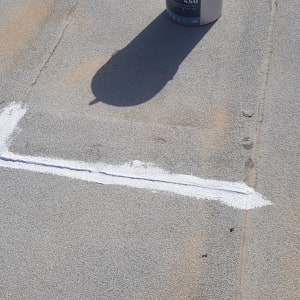 פס לבן צבוע על משטח אפור עם פחית צבע