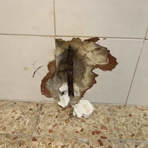 צינור חשוף בקיר עם ניירות טואלט על הרצפה