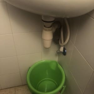 כיור עם דלי ירוק מתחת לצנרת