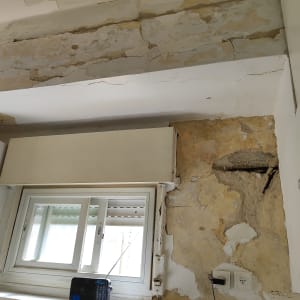 קיר מתקלף עם סימני רטיבות ותיקונים