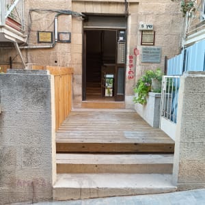 כניסה עם שביל עץ, צמחייה ופרחים בצדדים