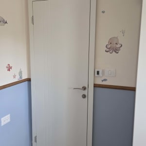 דלת לבנה עם ידית מתכת בחדר ילדים מעוצב