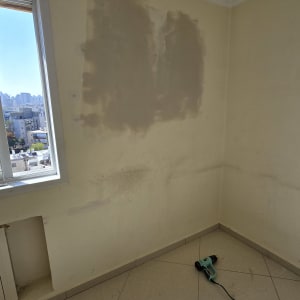 קיר עם תיקוני צבע וכלי עבודה על הרצפה