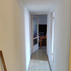 מסדרון צבוע בלבן עם דלת פתוחה ומקל צביעה