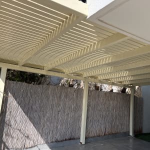 פרגולה מעץ עם גדר במבוק בחצר