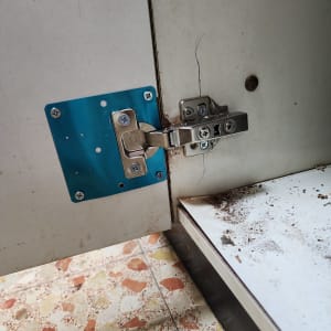 ציר מתכת על דלת ארון מטבח עם לוח חיזוק כחול