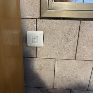 מתג חשמלי על קיר עם אריחים ומראה