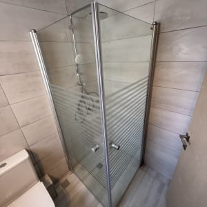 מקלחון זכוכית עם דלתות מתכת בחדר אמבטיה