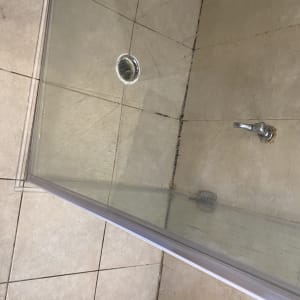 מקלחון עם דלת זכוכית ורצפת אריחים