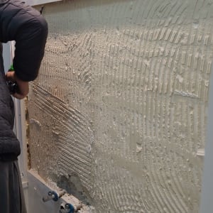 אדם עובד על קיר עם כלי עבודה