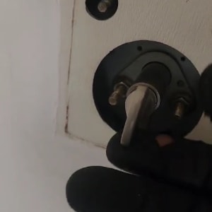 יד עם כפפה מתקינה מנעול בדלת